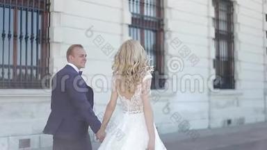 一对夫妇走在大皇宫附近。 优雅的新郎和新娘穿着婚纱。 爱情